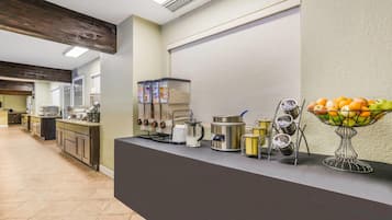Un espace cuisine comprenant un long comptoir, divers appareils électroménagers et un panier de fruits.