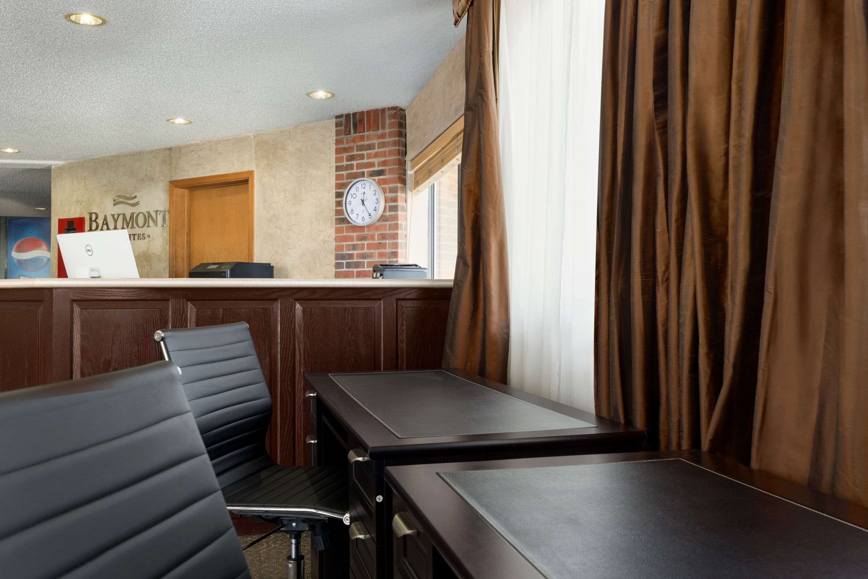 A hotel reception area with a clock, a desk, and seating.