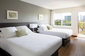 A hotel room with two beds, a city view, and artwork on the walls.