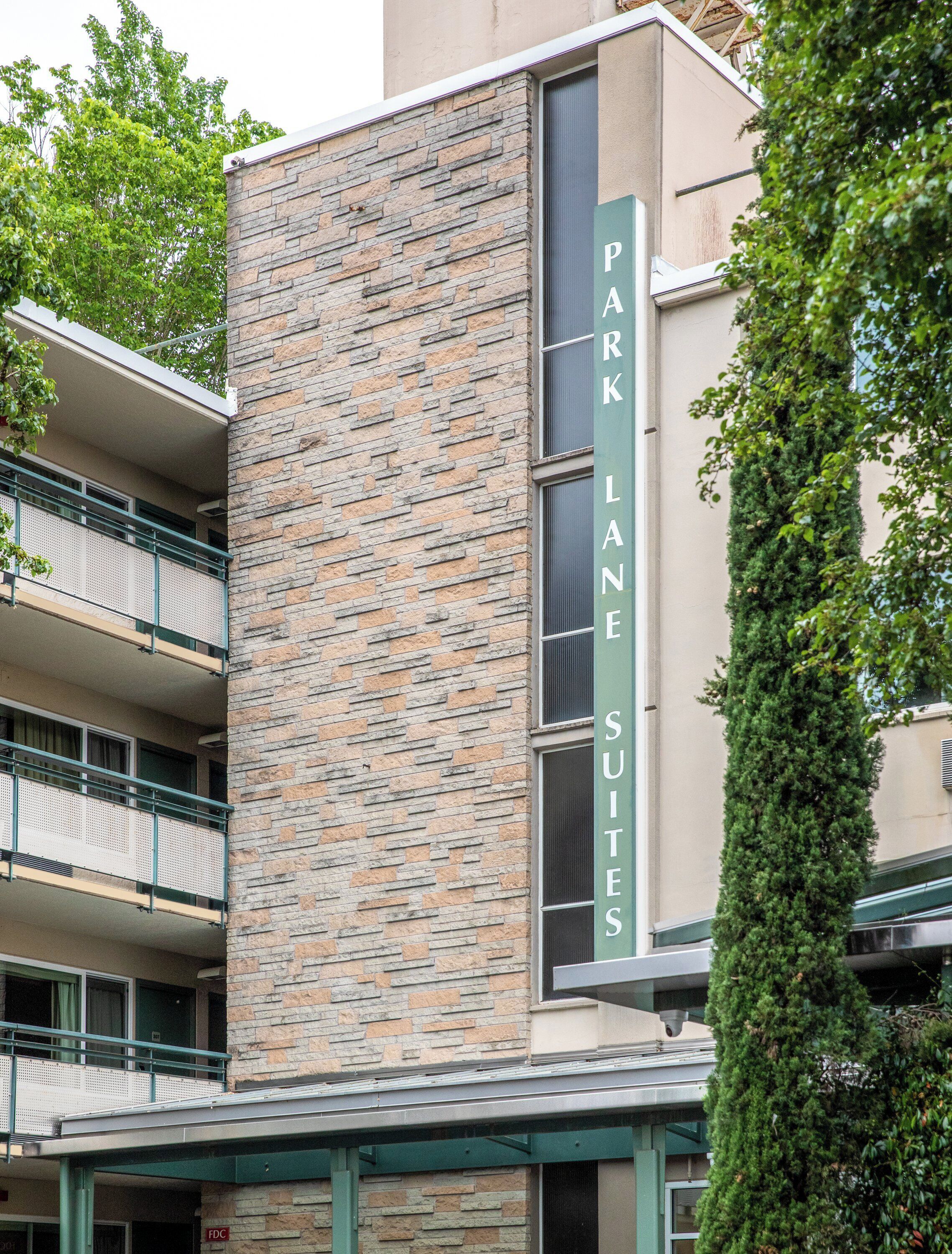 A building with a stone facade and a sign reading "Park Lane Suites."
