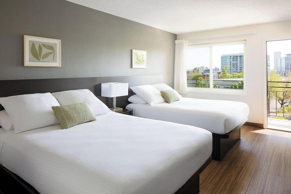 A hotel room with two beds, a city view, and a balcony.