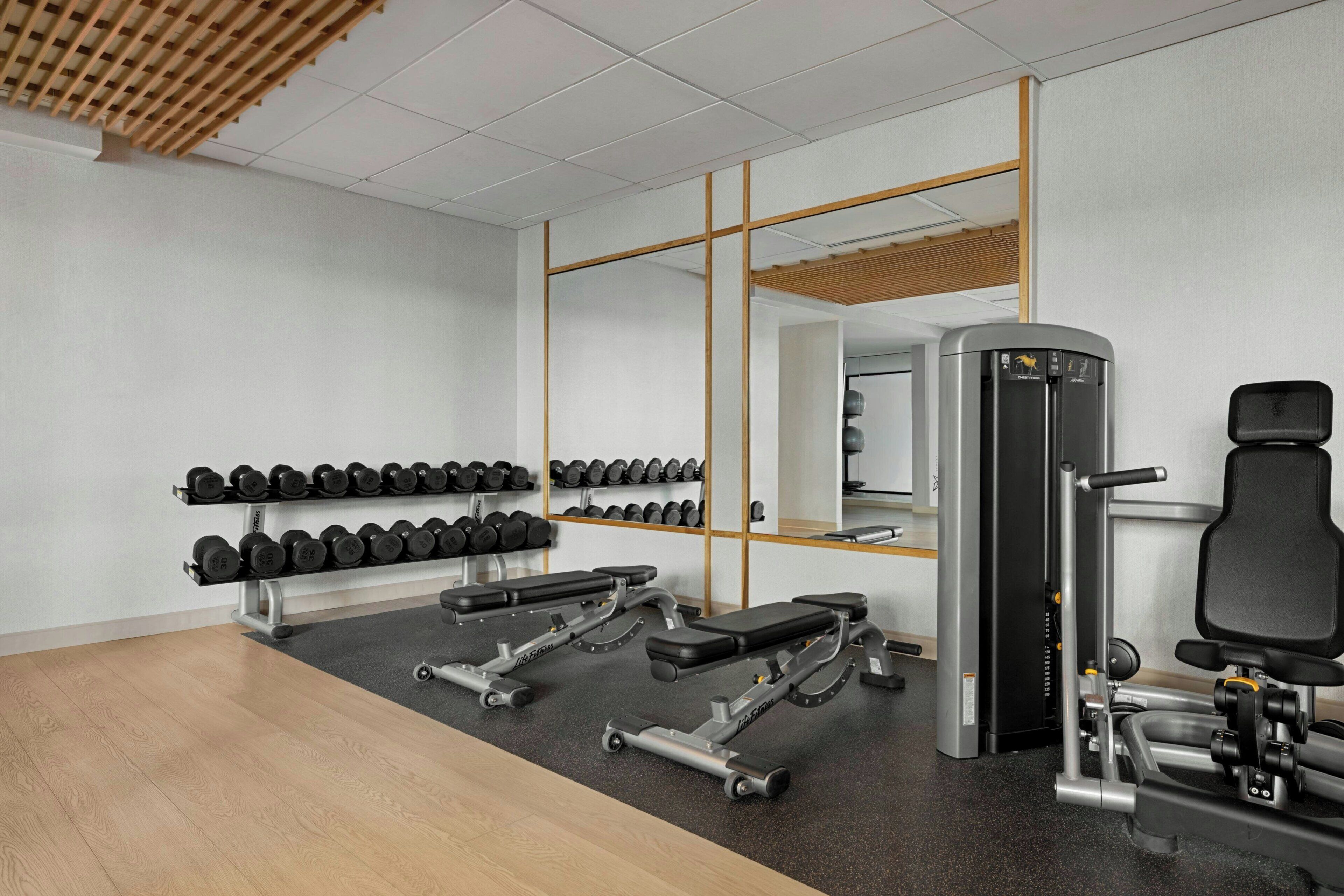 A gym with weightlifting equipment, dumbbells, and cardio machines.
