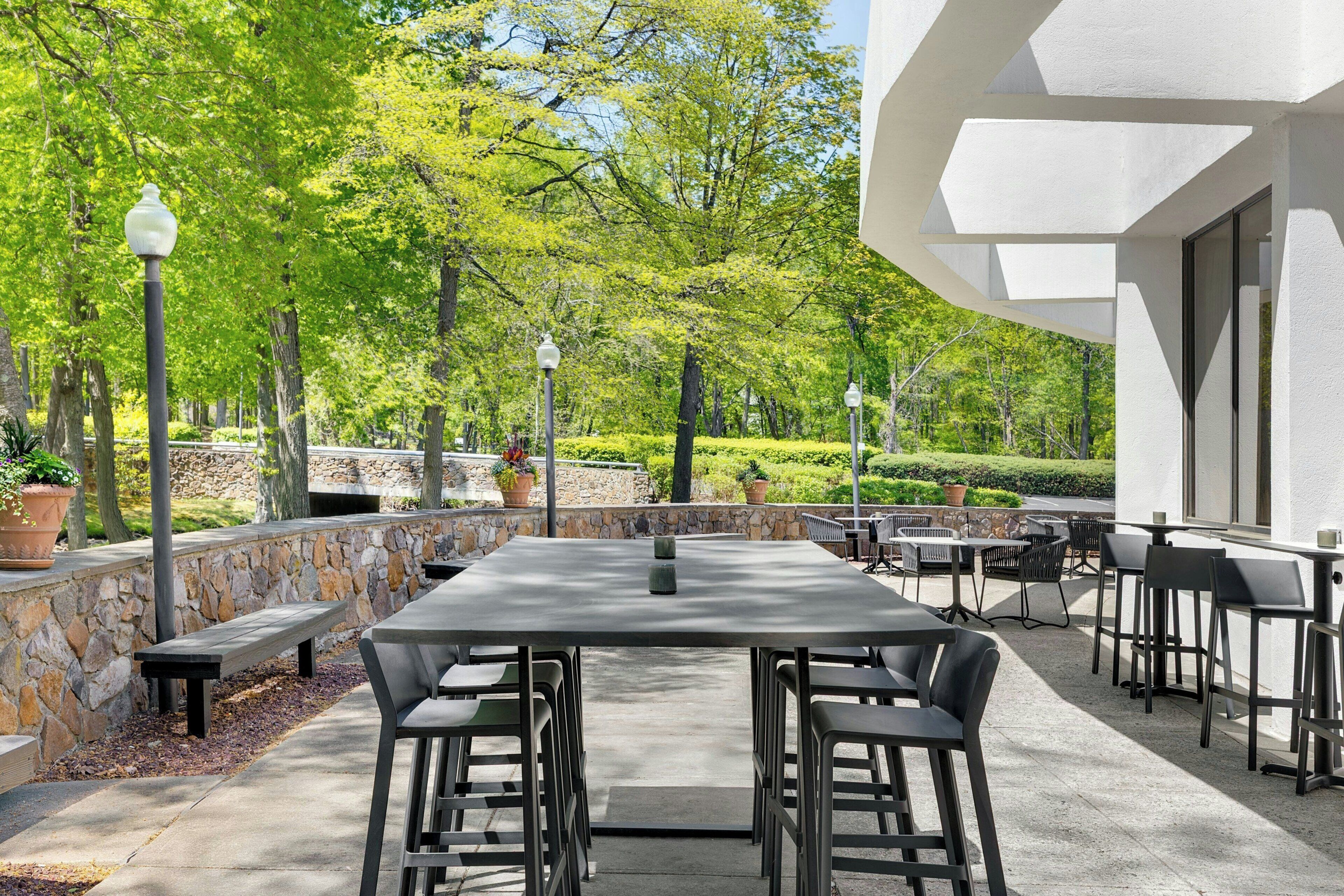 Une terrasse extérieure avec un mur en pierre, des bancs et des tables.