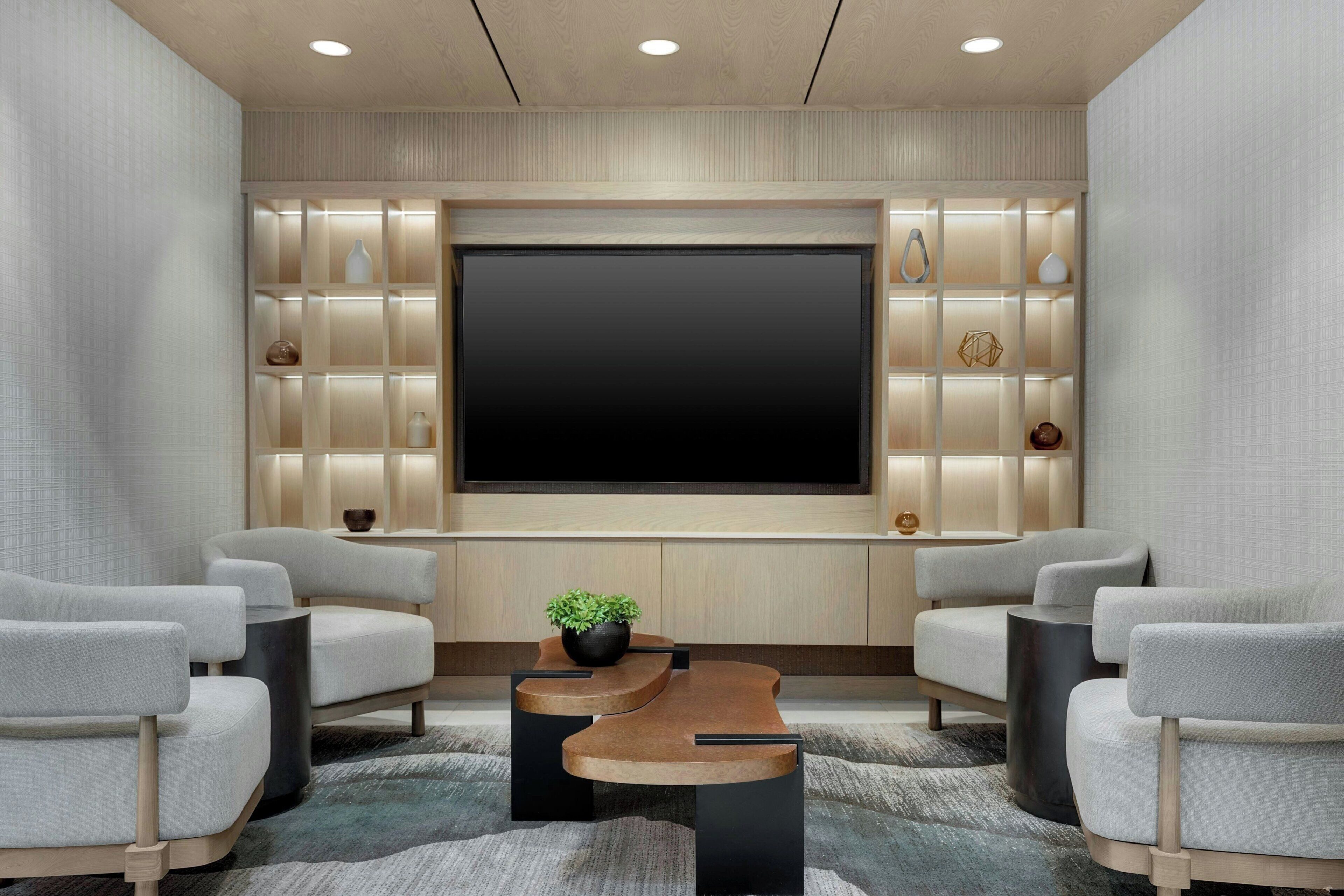 A modern home theater room with a large flat-screen TV, comfortable seating, and a decorative wall unit.
