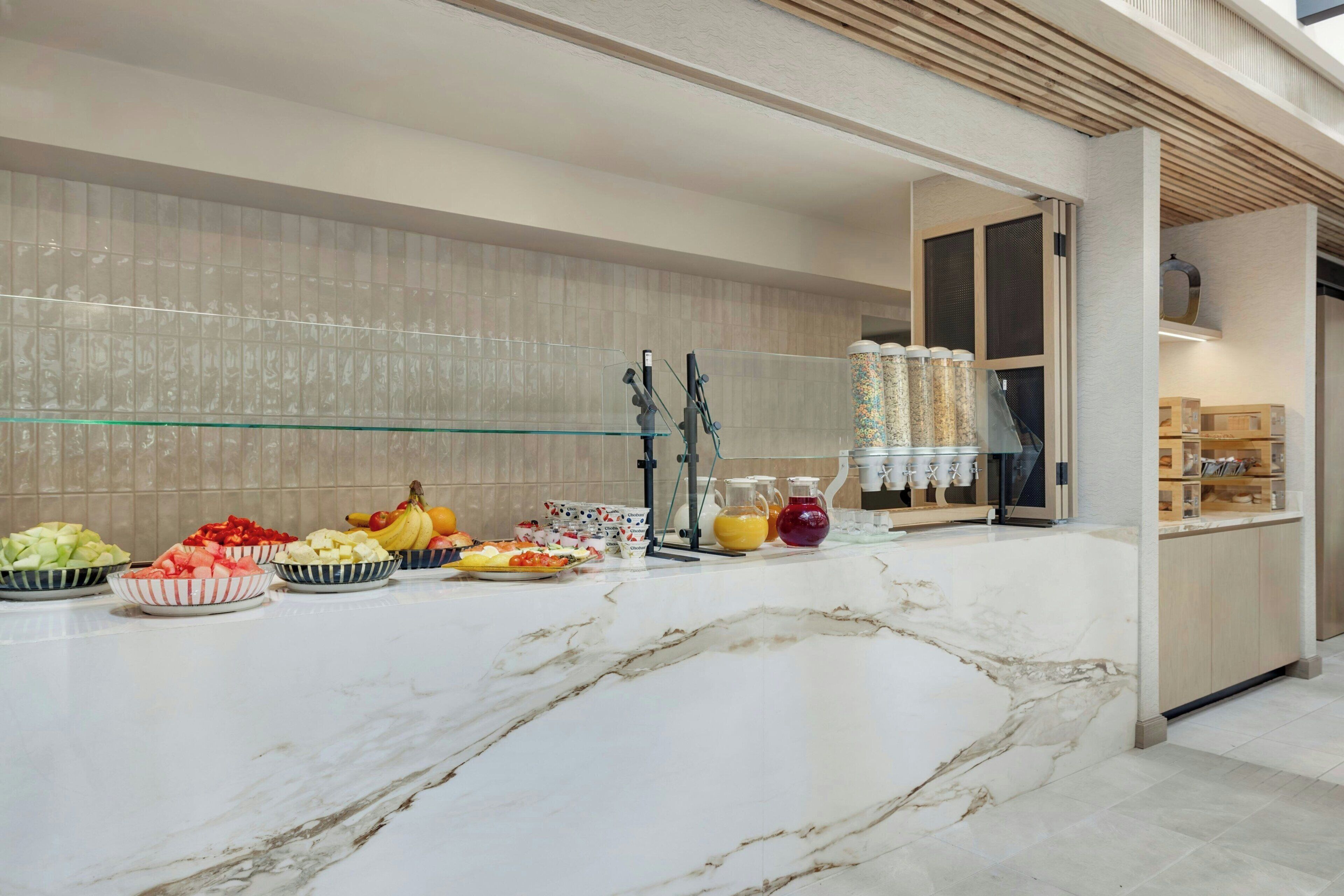 A marble countertop with fruit bowls, a water dispenser, and a glass shelf.