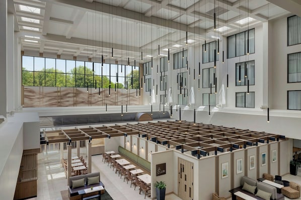 Un espacio interior amplio con techos altos, ventanas grandes y luminarias modernas.