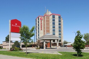 A Ramada hotel with a prominent red sign, a covered entrance, and a parking lot.