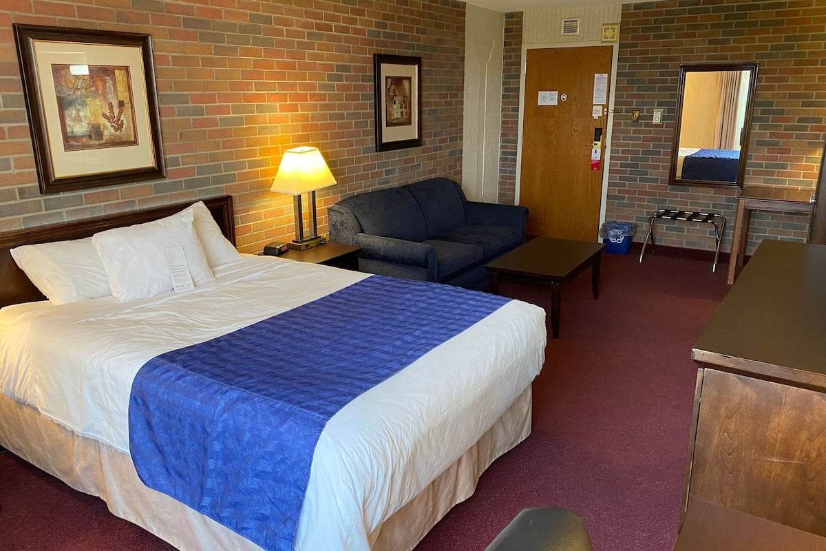 Una habitación de hotel con una cama grande, un sofá, un escritorio y un espejo.