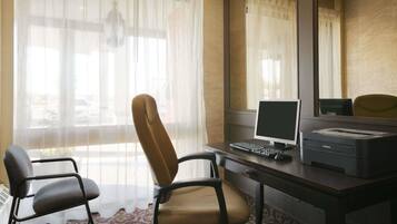 Een hotelkamer met een bureau, twee stoelen, een computer en een printer.