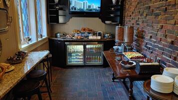 Un comptoir-repas équipé d’un téléviseur diffusant des images d’un bâtiment d’hôpital, d’un réfrigérateur rempli de boissons et d’un buffet proposant des fruits et des viennoiseries.