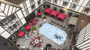 Un espace extérieur aménagé en terrasse, avec une piscine, des parasols rouges et des coins salon.