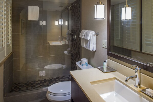 A modern bathroom with a glass-enclosed shower, a toilet, a sink with a mirror, and a towel rack.