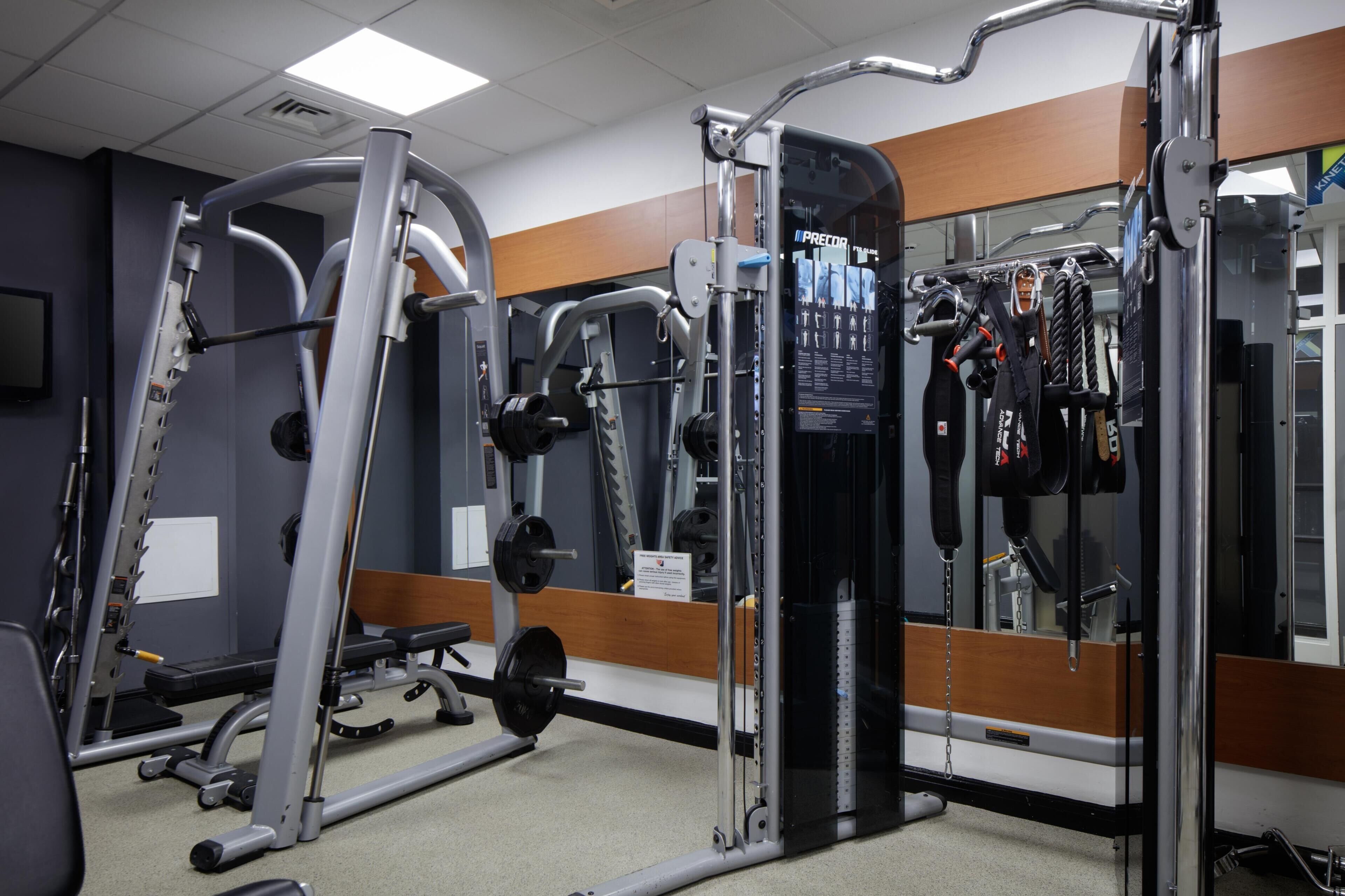 A gym with weightlifting equipment, a bench, and a mirror.