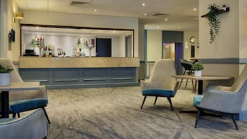 A hotel lobby with a reception desk, seating area, and a clock on the wall.
