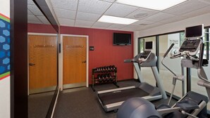 A fitness room with treadmills, dumbbells, and a television.