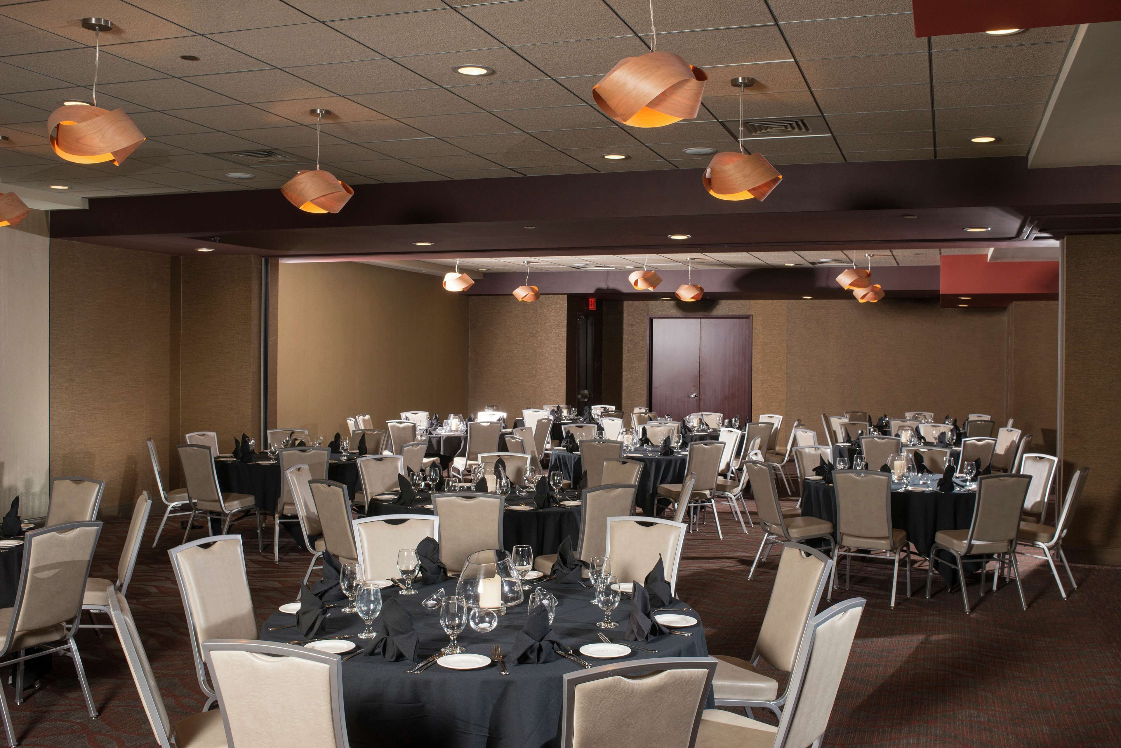 A banquet hall with multiple round tables set for dining, each with chairs and table settings.