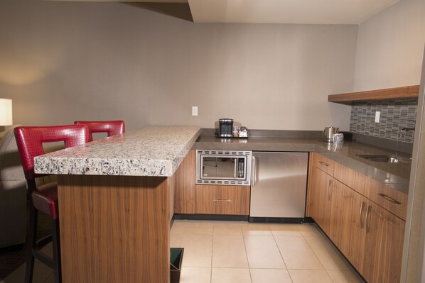 A modern kitchen with wooden cabinets, a granite countertop, a built-in microwave, and a stainless steel sink.