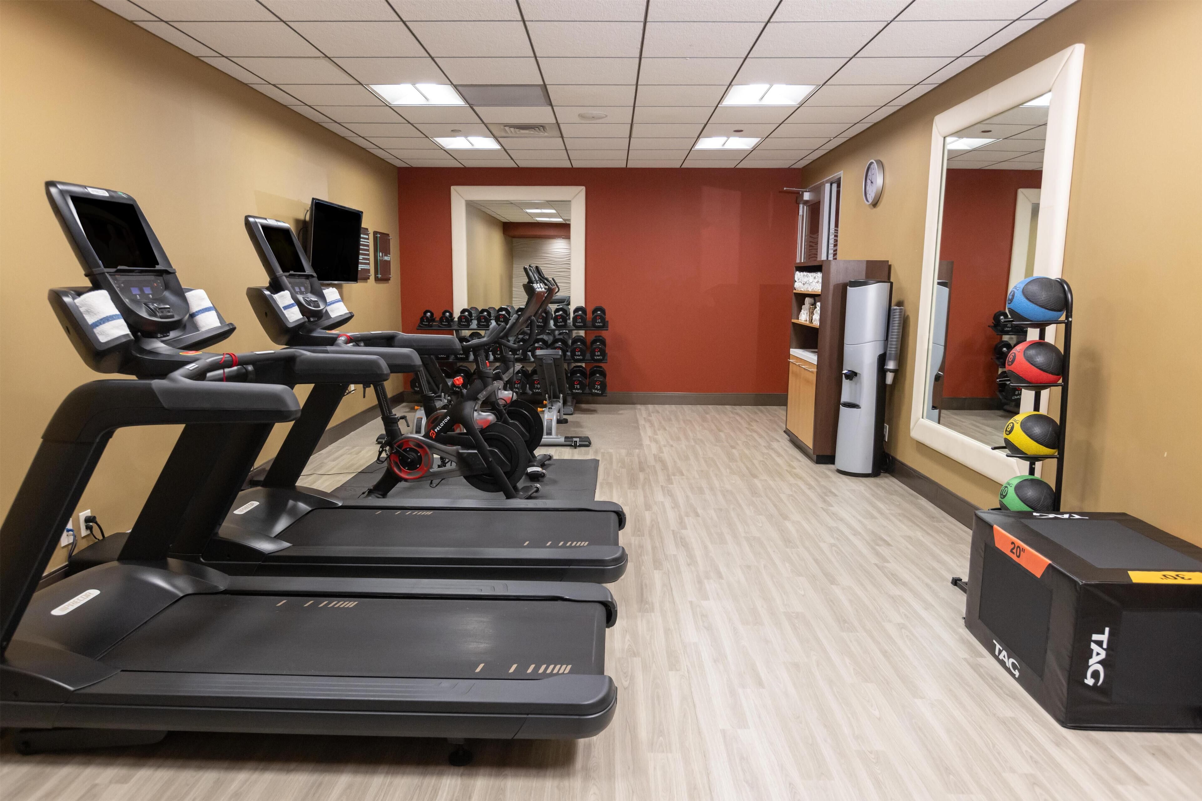 A gym with treadmills, weight machines, and exercise balls.