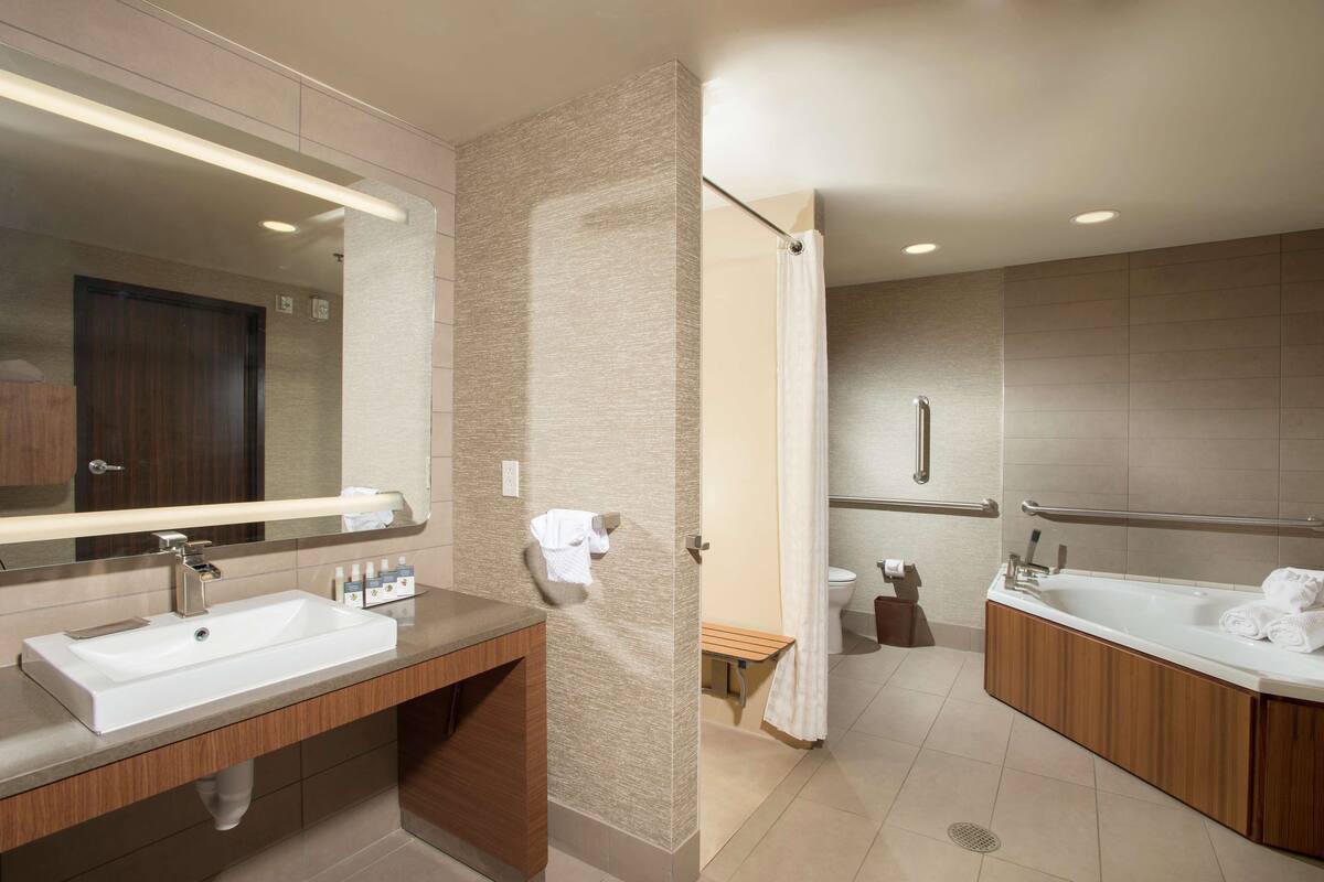A modern bathroom with a large sink, mirror, and bathtub.