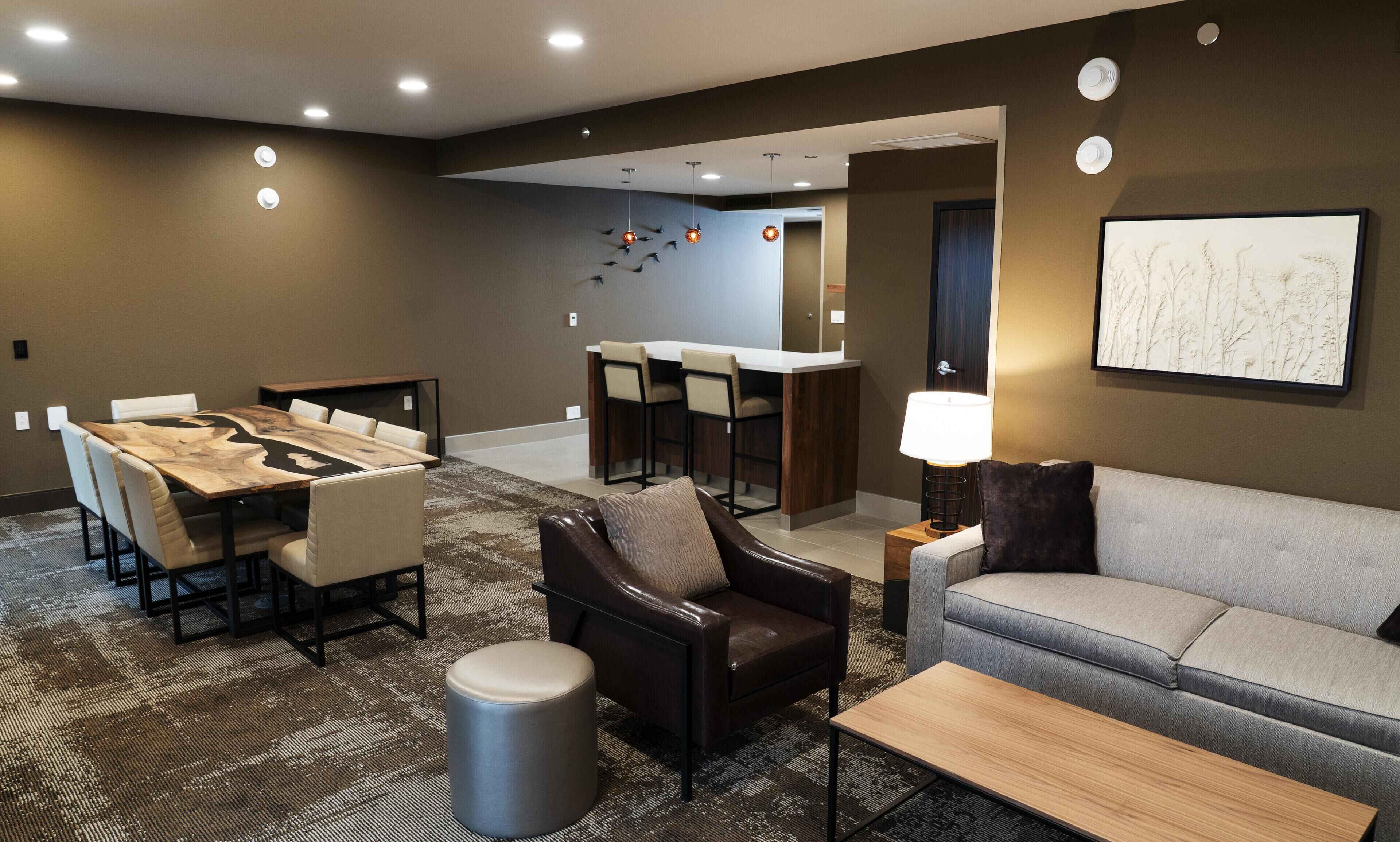 Ein modernes Hotelzimmer mit Essbereich, einer Couch, einem Couchtisch und einer Lampe.