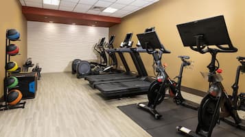 A gym with treadmills, stationary bikes, and a wall-mounted TV.
