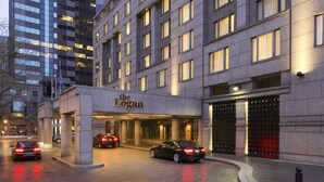 A hotel entrance with a modern facade, a clear sign reading "The Logan," and a parking area with cars. - The Logan Philadelphia, Curio Collection by Hilton (Philadelphia)