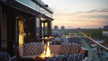 A rooftop bar with outdoor seating and a fire feature.