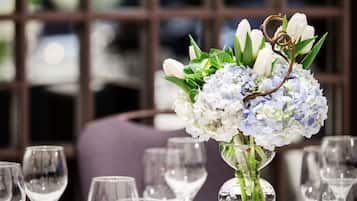 A dining table set with clear glassware and a centerpiece of white and blue flowers.