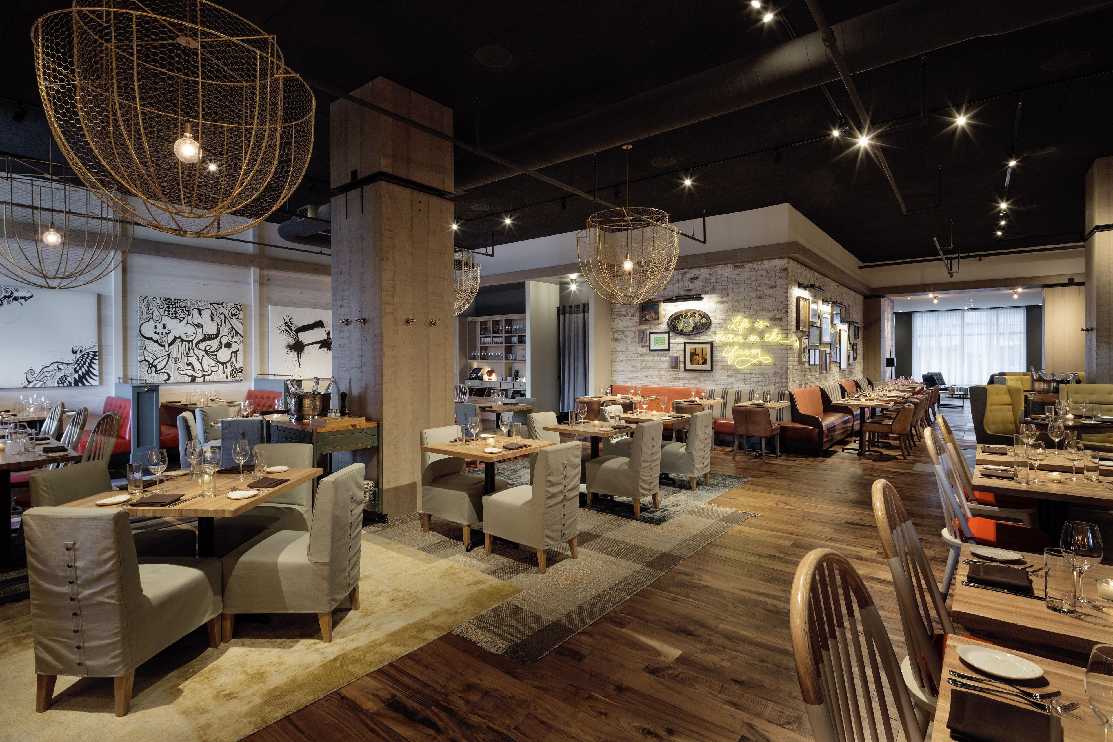 Un restaurante espacioso con techos altos, paredes de ladrillo visto e iluminación moderna.