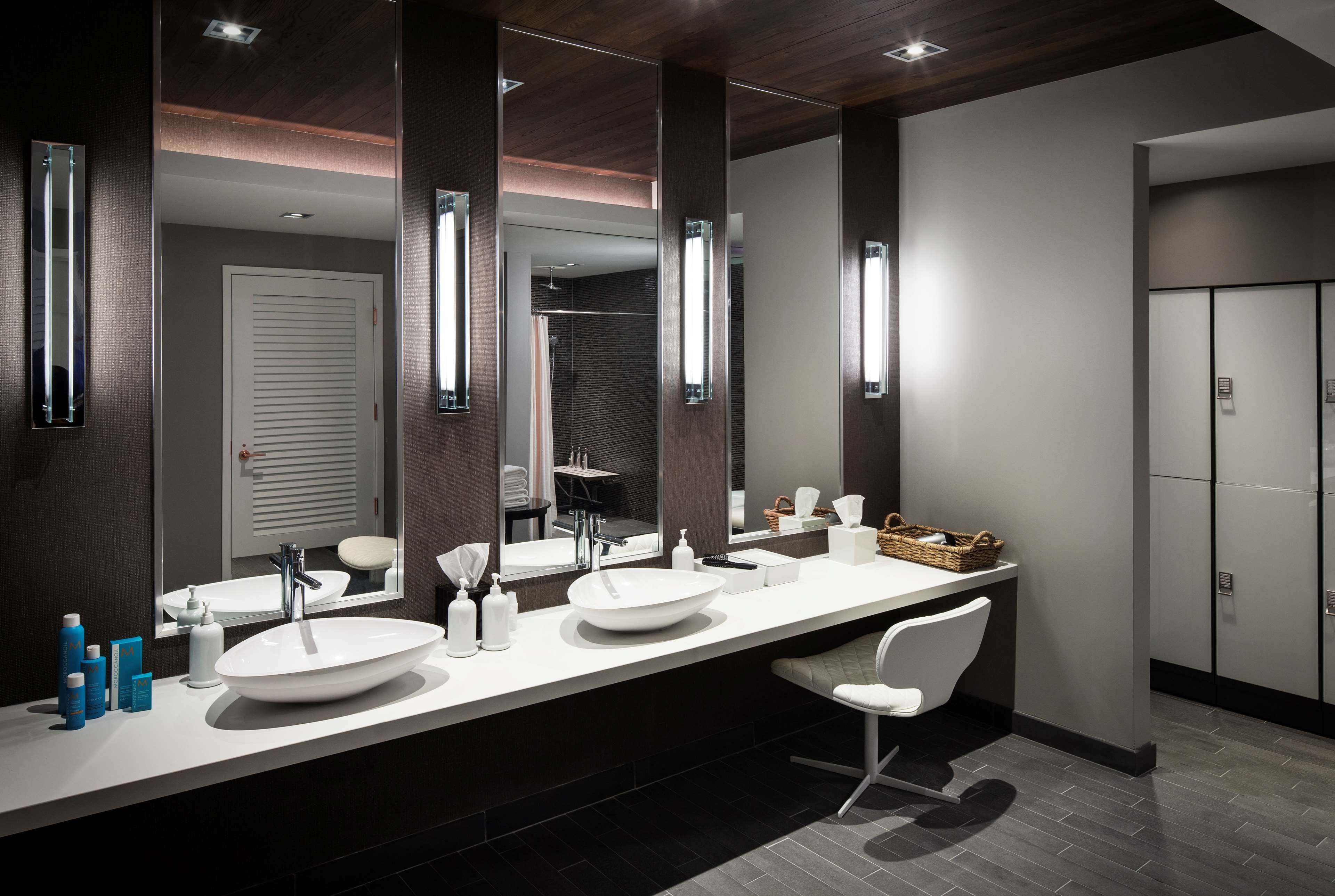 A modern bathroom with two sinks, a large mirror, and a white chair.