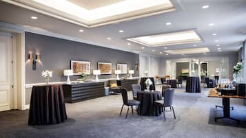 Um lobby moderno de hotel com balcão de recepção, área de estar e espaço para refeições.