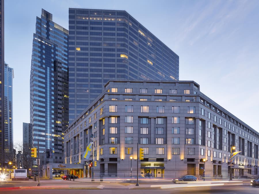 A modern hotel with a corner location, featuring a prominent entrance and a rooftop lounge.