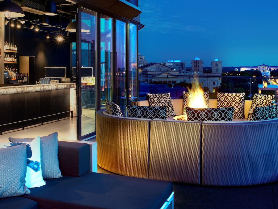 Un bar en la azotea con chimenea, zona de estar y vistas a la ciudad.