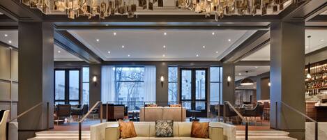 A spacious lobby with a central seating area, a staircase, and a bar.