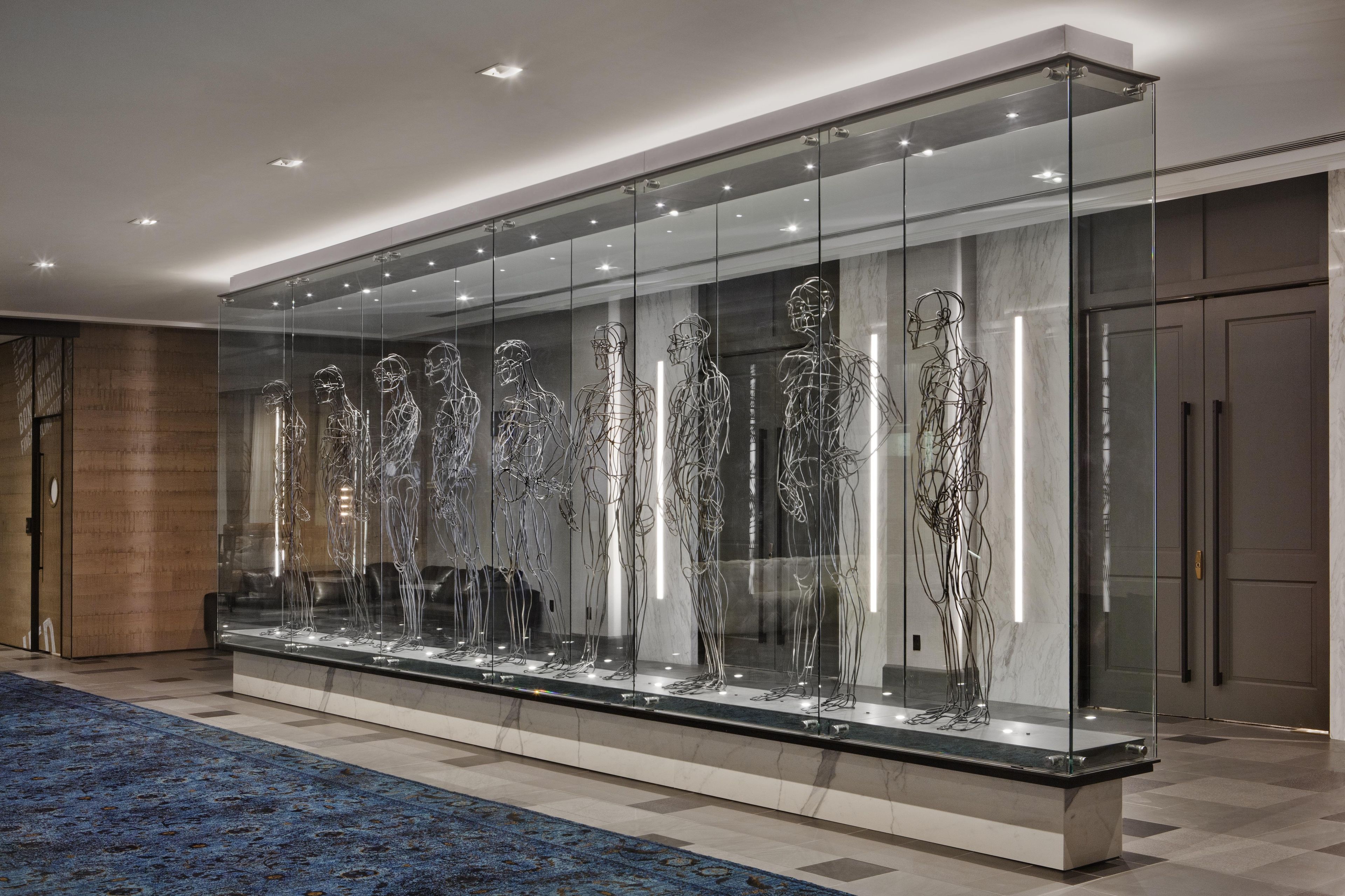 A modern hotel lobby with a long glass display case containing abstract sculptures.