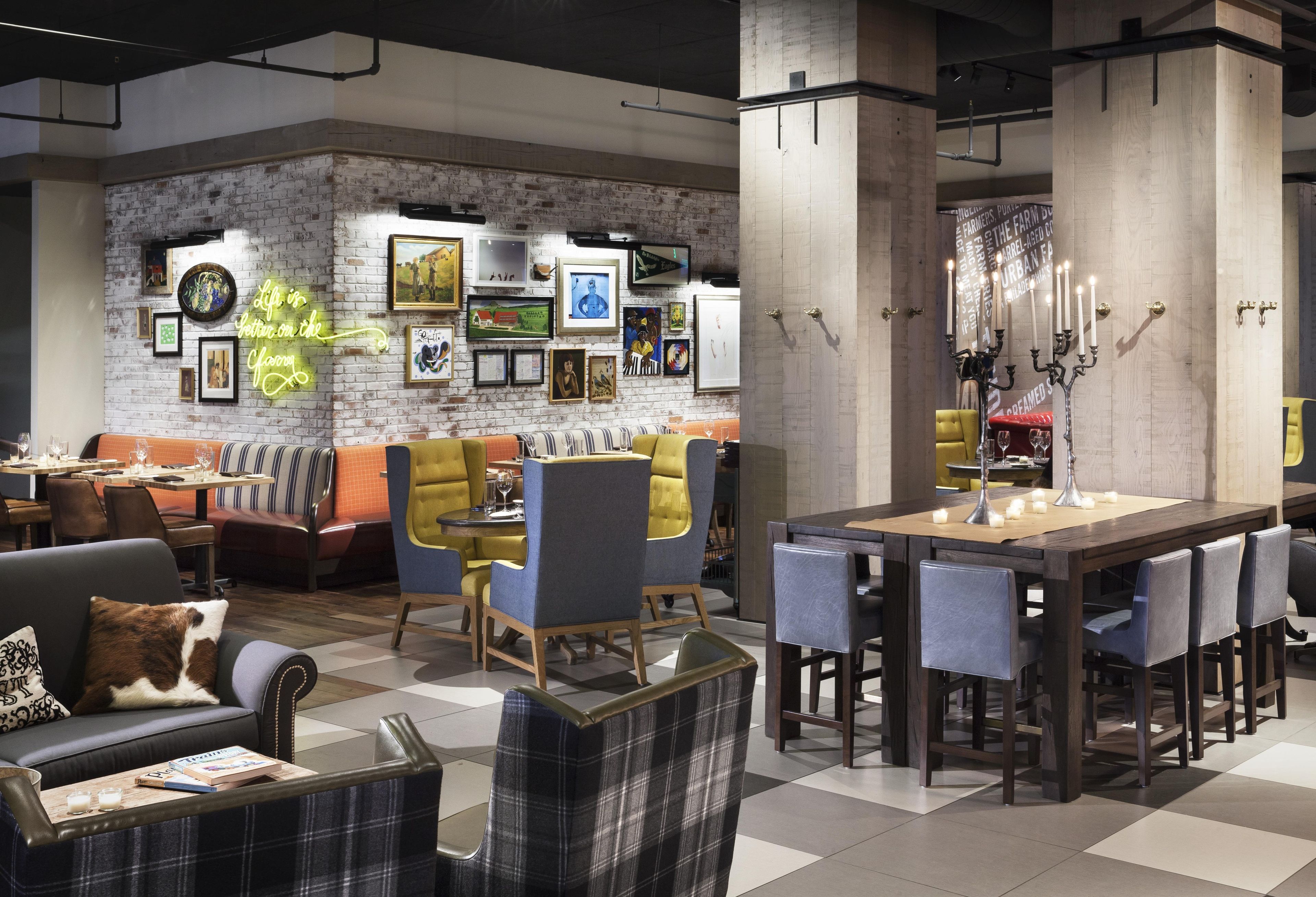 A modern lounge area with seating, a dining table, and a wall adorned with framed artwork.
