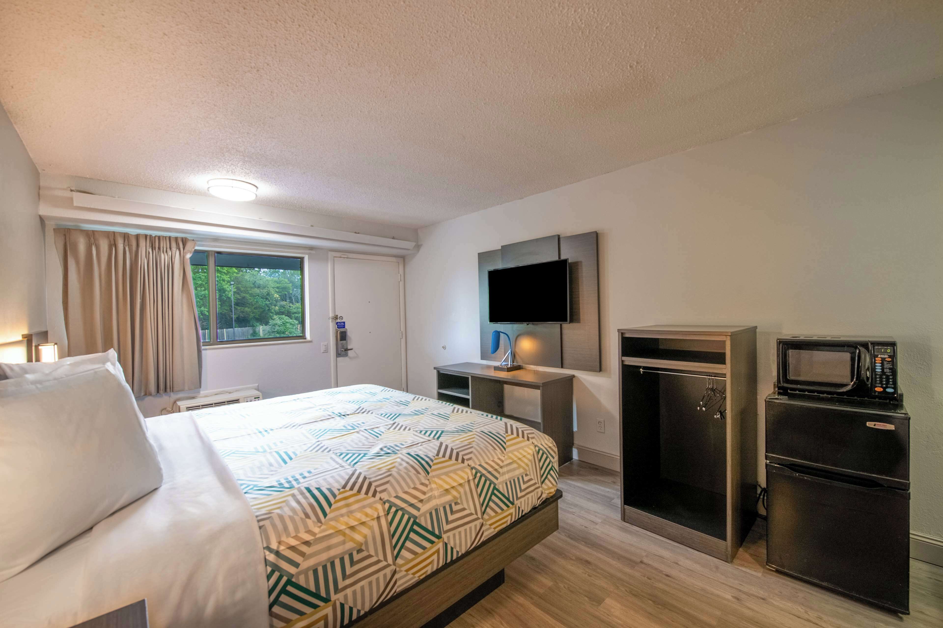 Une chambre d’hôtel équipée d’un lit, d’un bureau, d’une télévision, d’un four à micro-ondes et d’un réfrigérateur.