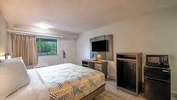 Une chambre d’hôtel équipée d’un lit, d’un bureau, d’une télévision, d’un four à micro-ondes et d’un réfrigérateur.