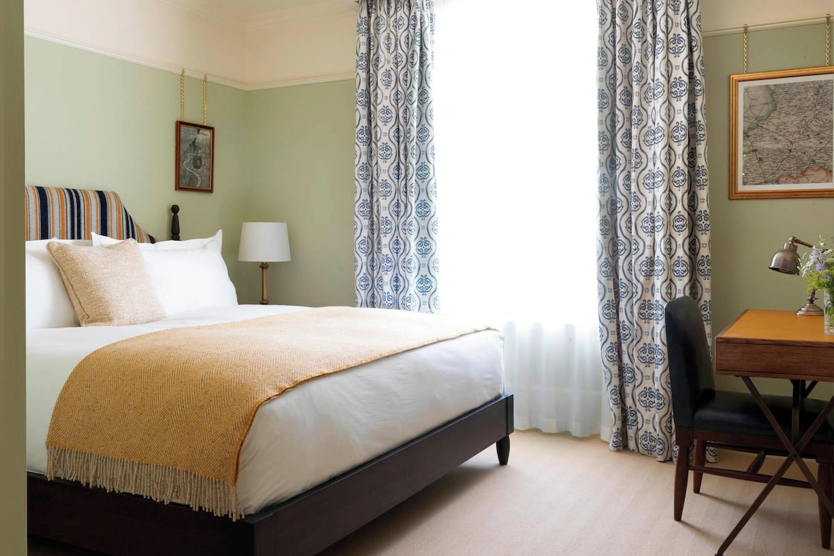 A neatly arranged bedroom with a bed, a desk, and a chair.