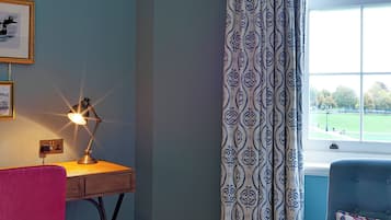 A room with a desk, chair, and a window with patterned curtains.