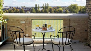 A terrace with two chairs and a table set for breakfast, overlooking a cityscape. - University Arms, Autograph Collection (Cambridge)