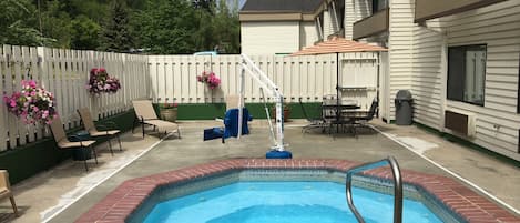A backyard with a swimming pool, patio furniture, and hanging flower baskets.