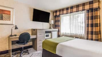 A hotel room with a bed, desk, chair, television, and a window with curtains.