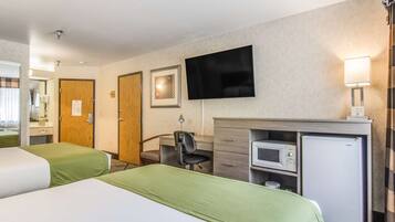 Une chambre d’hôtel avec deux lits, un bureau avec une chaise, une télévision, un four à micro-ondes et un réfrigérateur.