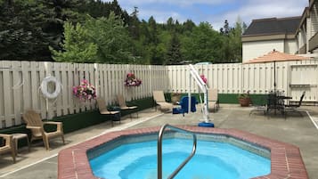 Um quintal com piscina, móveis de pátio e cerca de madeira.