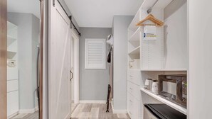 Un pasillo estrecho con una puerta corredera, un microondas, un refrigerador y un perchero.