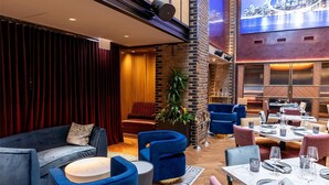 A spacious indoor area with a high ceiling, a dining area with tables and chairs, and a seating area with sofas and armchairs. - Thompson Chicago, by Hyatt (Chicago)