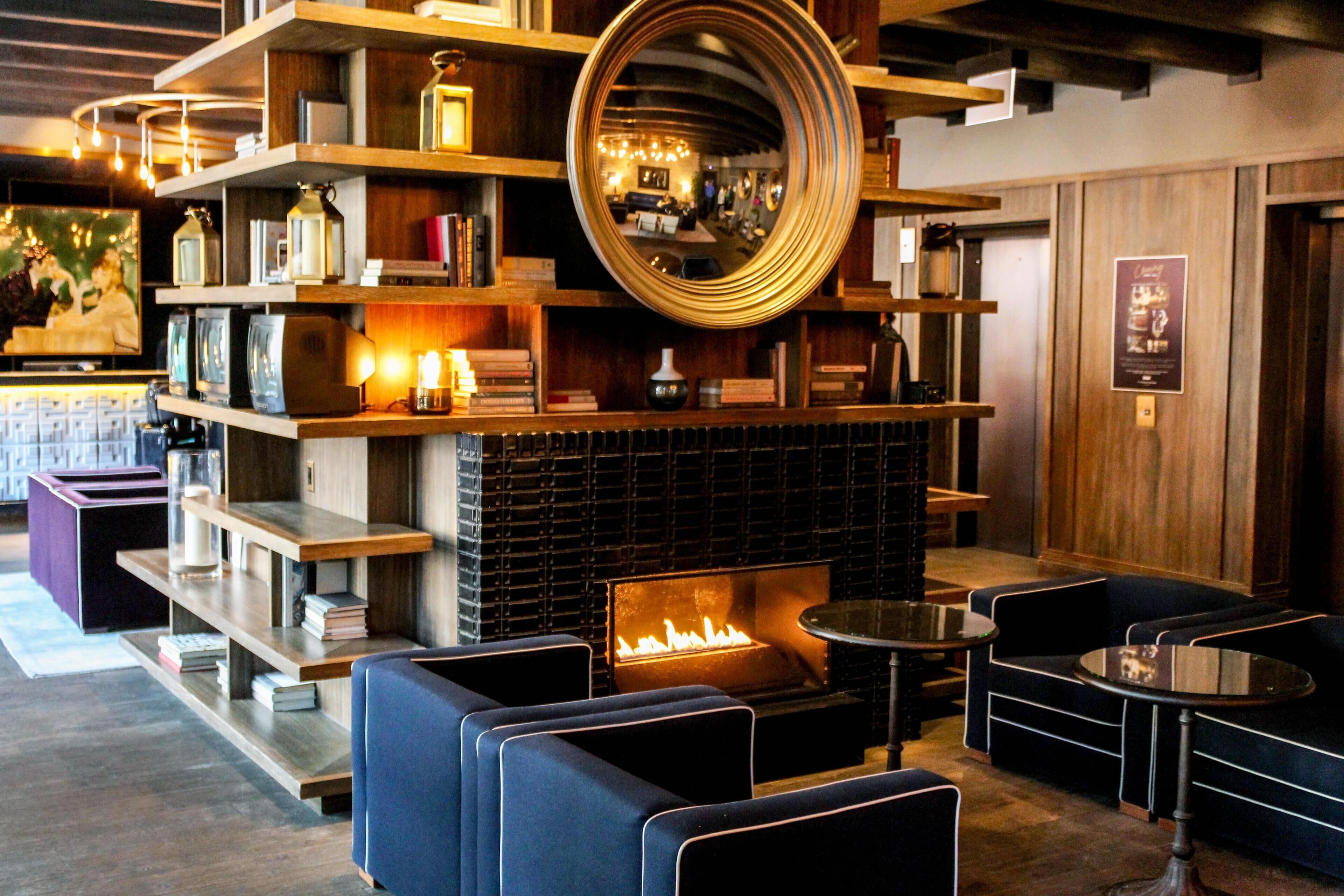 A cozy lounge area with a fireplace, bookshelves, and comfortable seating.