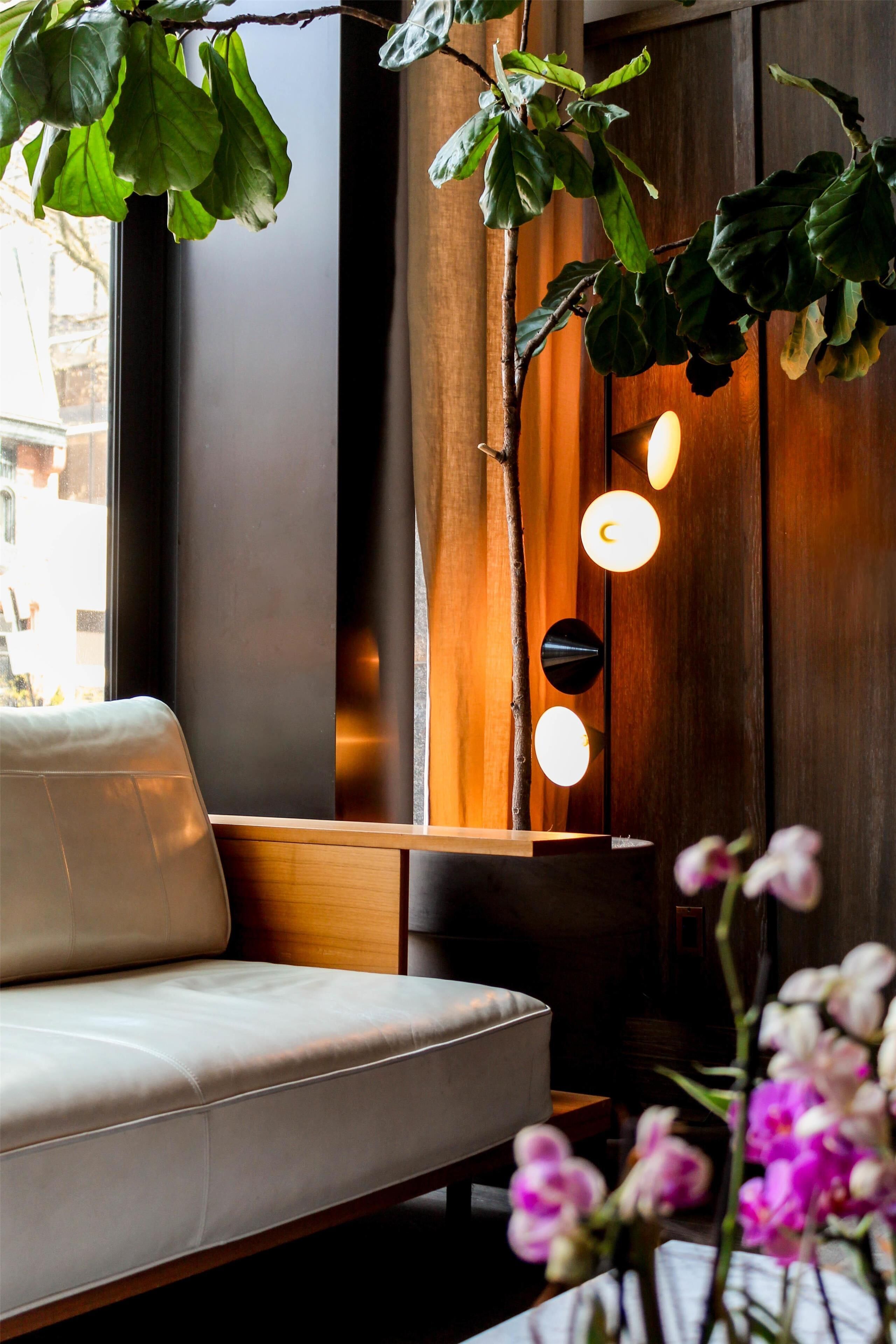 Een modern interieur met een bank, een wand van houten panelen en hanglampen.