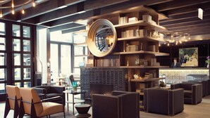 A modern lobby with a large mirror, bookshelves, seating areas, and a reception desk. - Thompson Chicago, by Hyatt (Chicago)